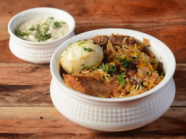 Traditionelles Hyderabadi Chicken dum Biryani aus Basmati-Reis, gekocht mit Masala-Gewürzen, serviert mit gekochtem Ei und Zwiebel-Raita mit selektivem Fokus