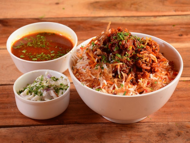 Traditionelles Hyderabadi Chicken dum Biryani aus Basmatireis, gekocht mit Masala-Gewürzen, serviert mit Onion Raita und Salan Selective Focus