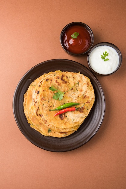 Traditionelles indisches Essen Aloo Paratha oder Kartoffel gefülltes Fladenbrot. serviert mit Tomatenketchup und Quark auf buntem oder hölzernem Hintergrund. Selektiver Fokus