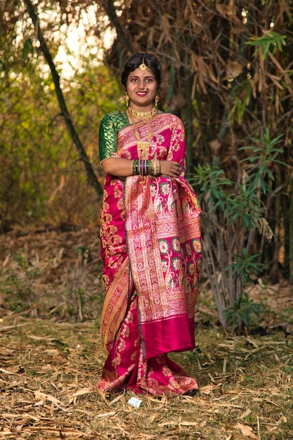 Traditionelles indisches schönes junges Mädchen in Sari, das im Freien im Park posiert