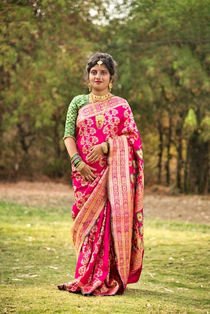 Traditionelles indisches schönes junges Mädchen in Sari, das im Freien im Park posiert