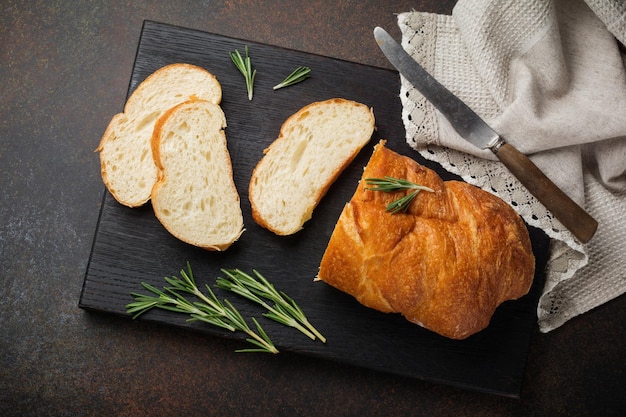 Traditionelles italienisches Ciabatta-Brot mit Rosmarin auf dunklem Stein- oder Betonhintergrund Selektiver FokusDraufsicht