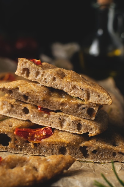 Foto traditionelles italienisches hausgemachtes focaccia-brot mit tomaten und rosmarin auf rustikalem hölzernem hintergrund