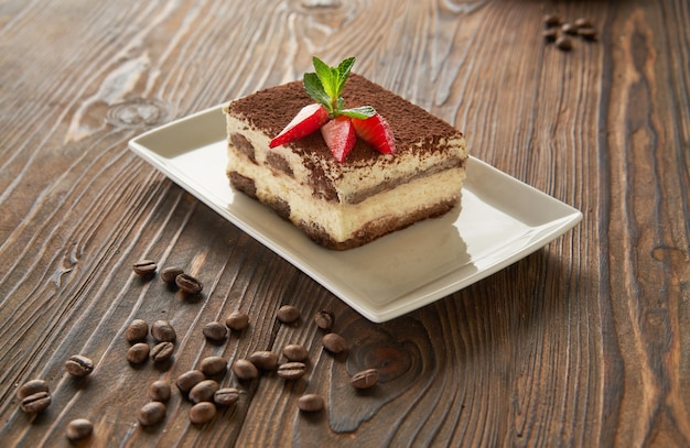 Traditionelles italienisches Tiramisu-Dessert auf Holzhintergrund der weißen Platte mit Kaffeebohnen