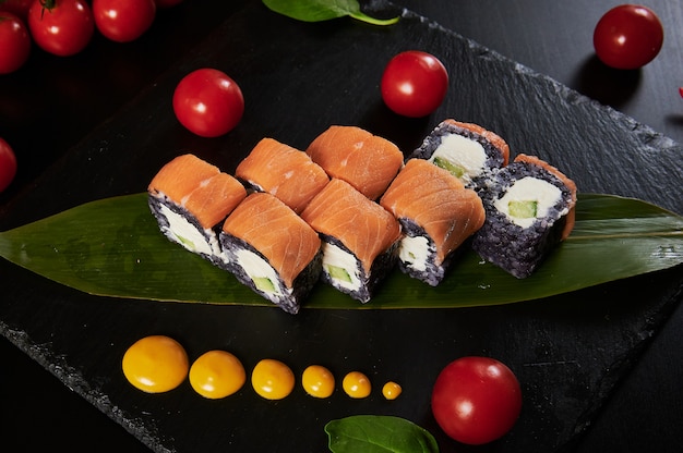 Traditionelles japanisches Essen - Sushi, Brötchen und Soße auf einem schwarzen Hintergrund.