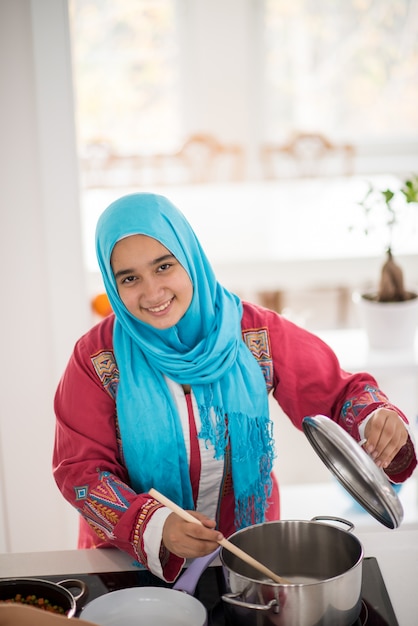 Traditionelles junges Mädchen des Moslems, das Lebensmittel in der Küche macht