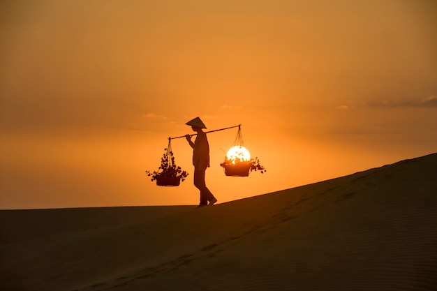 Traditionelles Kleid der Frau mit Vietnamkultur auf Sandune während Sonnenuntergang, traditionelles Kostüm