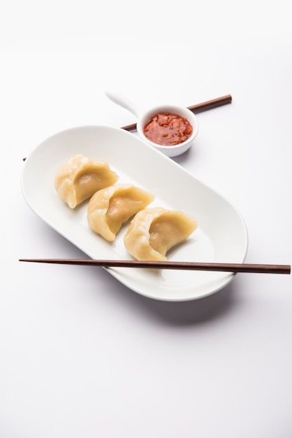 Traditionelles Knödel-Momos-Essen aus Nepal, serviert mit Tomaten-Chutney auf stimmungsvollem Hintergrund. Selektiver Fokus