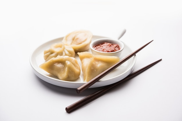 Traditionelles Knödel-Momos-Essen aus Nepal, serviert mit Tomaten-Chutney auf stimmungsvollem Hintergrund. Selektiver Fokus