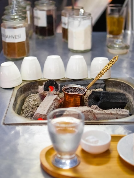 Traditionelles Kochen von türkischem Kaffee auf Kohlen mit Wasser und türkischem Genuss