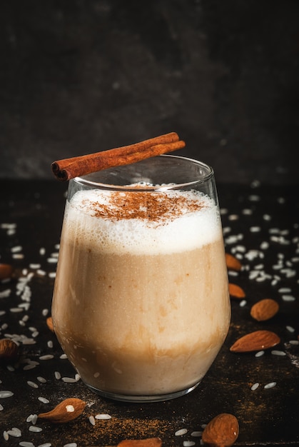 Traditionelles mexikanisches Getränk Horchata Latte Kaffee gemischt mit Horchata, einem Cocktail aus Mandeln, Reis, Vanille und Zimt. Auf einem schwarzen Betontisch mit Zutaten.