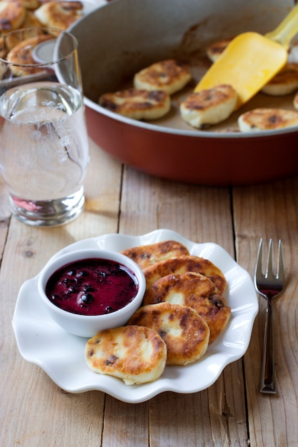 Traditionelles russisches Syrniki mit Rosinen. Süße Quarkpfannkuchen mit Blaubeersauce