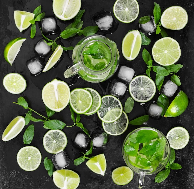 Traditionelles Sommergetränk Mojito mit Limettenminze und Eis auf schwarzer rustikaler Oberfläche Draufsicht