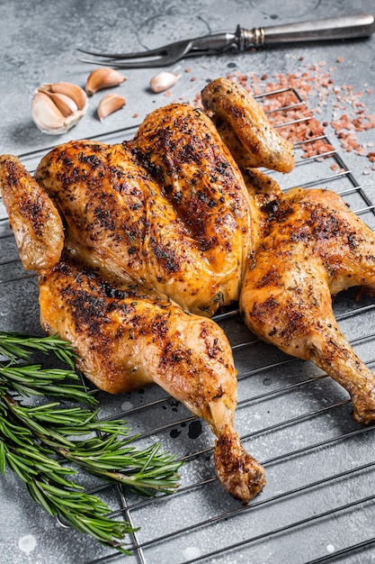 Traditionelles spatchcocked Grillhuhn auf Grill Grauer Hintergrund Ansicht von oben