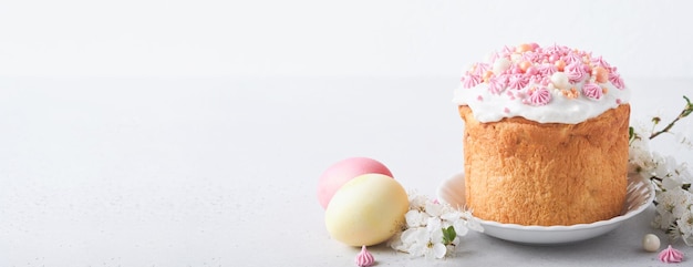 Traditionelles süßes Osterbrot oder Kuchen mit weißem Zuckerguss und Zuckerdekor farbige Eier und Kirschblütenzweig über weißem Tisch Verschiedene Osterkuchen im Frühling Fröhlicher Ostertag Selektiver Fokus