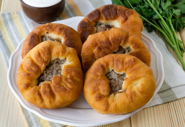 Traditionelles Tatar- und Bashkir-Gericht Belyashi. Gebratene Kuchen mit Hackfleisch und Zwiebeln öffnen.