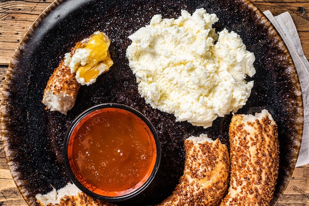 Traditionelles türkisches Frühstück - Kaymak Clotted Cream, Bagel Simit und Honig. Hölzerner Hintergrund. Ansicht von oben.