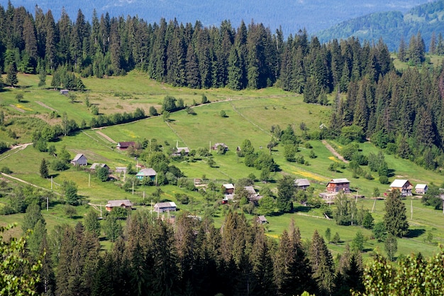 Traditionelles ukrainisches Dorf inmitten der Karpaten, die mit grünen Wäldern bedeckt sind