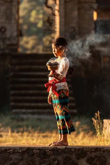 Traditionen des indonesischen Volkes. Ein kleines Mädchen aus Bali in der Nähe eines indonesischen Tempels.