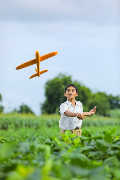 Träume vom Fliegen! indisches Kind, das mit Spielzeugflugzeug an der grünen Wiese spielt