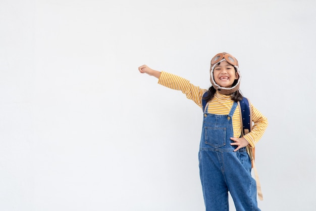 Träume vom Fliegen! kleines Kindermädchen, das mit einem Pilotenhut auf weißem Hintergrund spielt