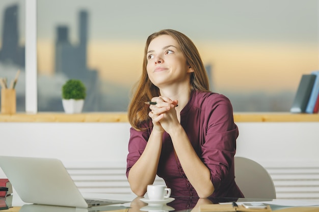 Träumende Frau am Arbeitsplatz