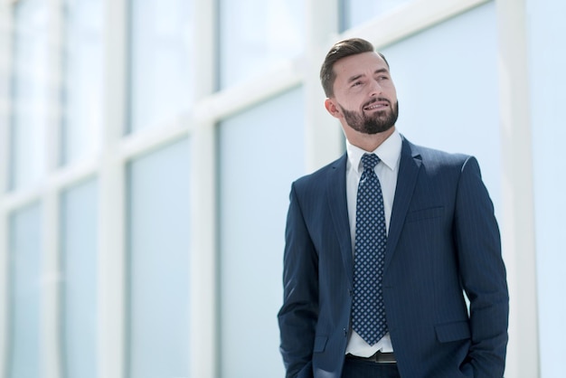 Träumender Geschäftsmann, der in einem hellen Büro steht