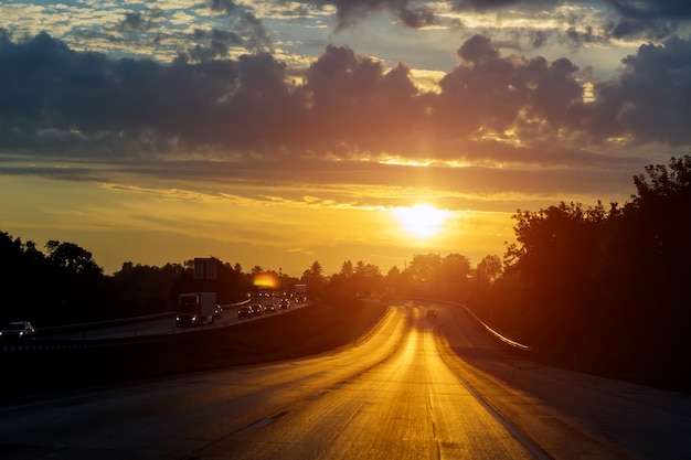 Tráfego noturno, carros na estrada na noite do pôr do sol