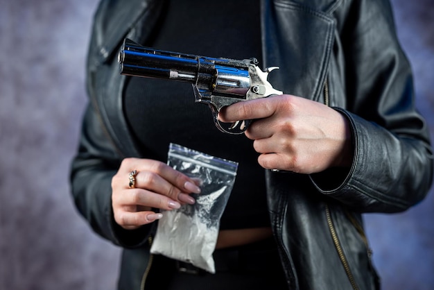 Traficante de mulher segura pistola de mão com pacote de plástico com pó branco