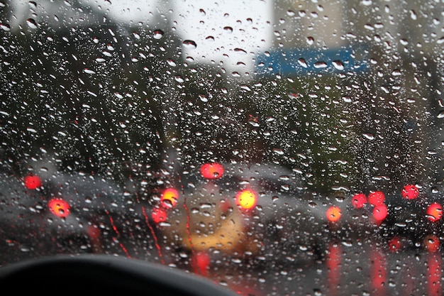 Tráfico de la calle de la ciudad a través del parabrisas del coche mojado