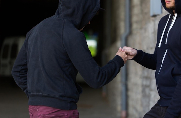 Foto tráfico de drogas, crimen, adicción y concepto de venta - cierre de adicto con dinero comprando dosis del traficante en la calle