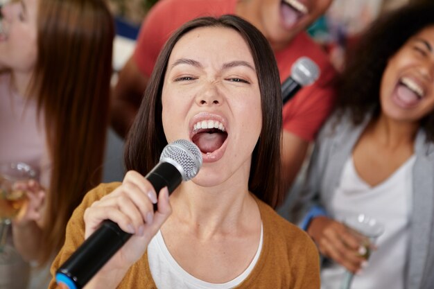 Traga o som, close-up, foto da bela jovem asiática segurando o microfone e cantando enquanto