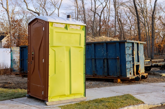 Tragbare chemische Toiletten für den Bau eines neuen Hauses und Müllcontainers voller Müll