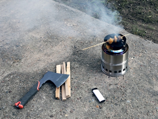 Tragbarer holzofen räuchert fleisch auf einem holzstab