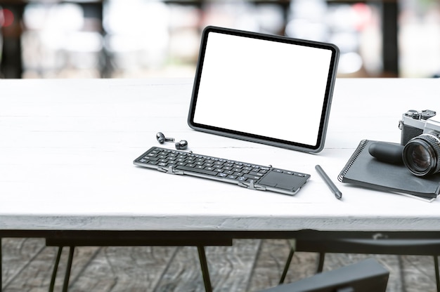 Tragbares Mockup-Tablet mit Tastatur und Gadget auf weißem Top-Tisch, leerer Bildschirm für die Produktanzeige.