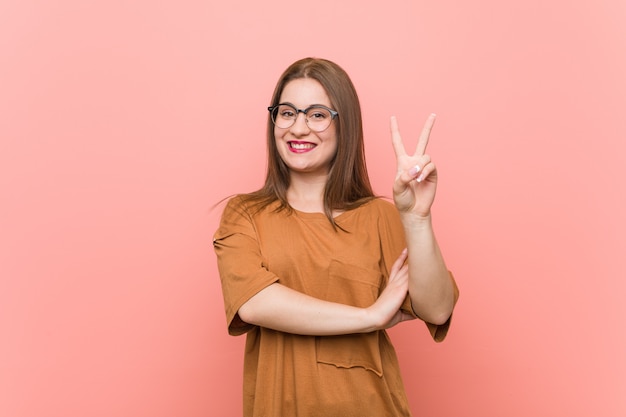 Tragende Brillen der jungen Studentenfrau, die Nummer zwei mit den Fingern zeigen.