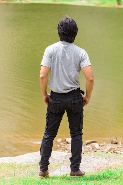 Tragende Frachthosen und -t-shirt des glücklichen Mannes, die neben dem Fluss stehen