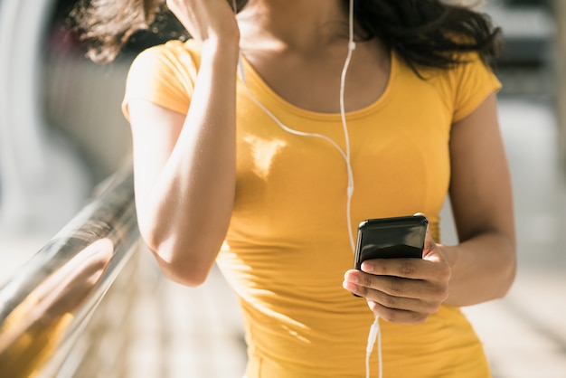 Tragende Kopfhörer der Frau, die Musik vom Smartphone hören