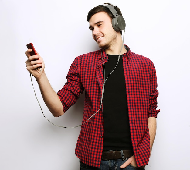 Tragende Kopfhörer des jungen Mannes und Halten des Handys