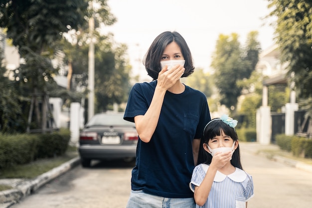 Tragende Maske der Asiatin und der kleinen jungen Tochter für verhindern Dämmerung PM 2,5 schlechte Luftverschmutzung.