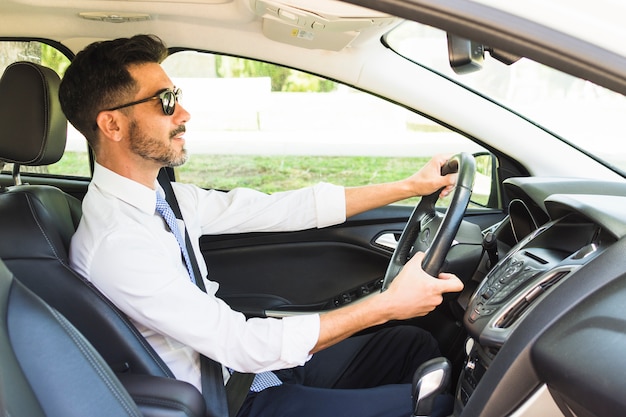 Tragende Sonnenbrille des stilvollen Geschäftsmannes, die das Auto fährt