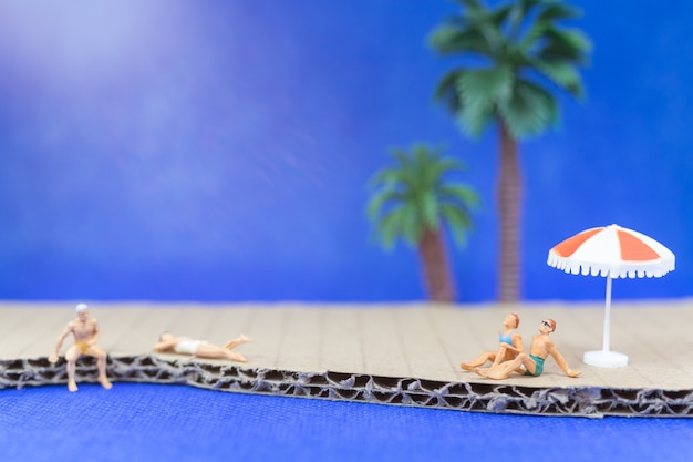 Tragender Badeanzug der Miniaturleute, der auf dem Strand sich entspannt