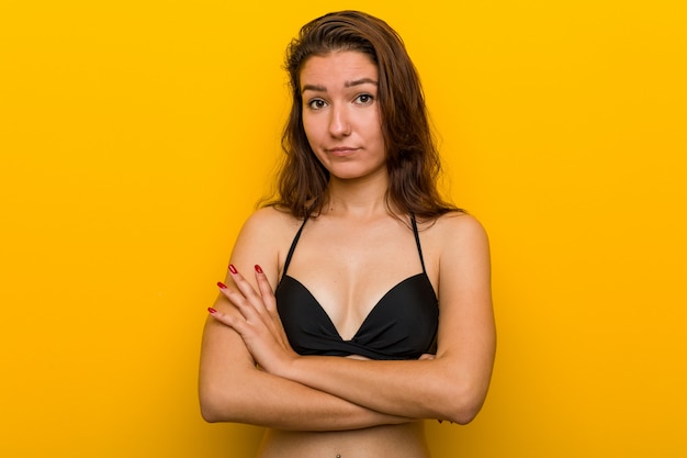 Tragender Bikini der jungen europäischen Frau, der herein mit sarkastischem Ausdruck unglücklich schaut.