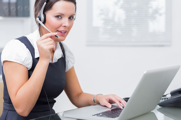 Tragender Kopfhörer der weiblichen Exekutive bei der Anwendung des Laptops am Schreibtisch