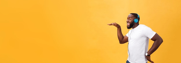 Tragender Kopfhörer des jungen Afroamerikanermannes und genießen Sie die Musik, die über gelbes Goldhintergrund tanzt