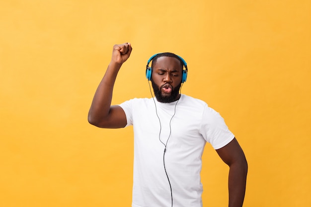 Tragender Kopfhörer des jungen Afroamerikanermannes und genießen Sie die Musik, die über gelbes Goldhintergrund tanzt