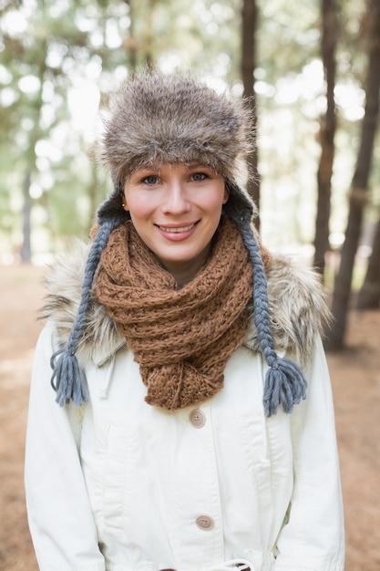 Tragender Pelzhut der Frau mit woolen Schal und Jacke im Holz