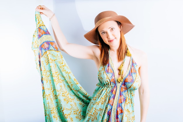 Foto tragendes sommerkleid der schönen jungen frau, hut auf weißem hintergrund mit dem raum, der strandkleidrock zeigt. sommerurlaub konzept. mode