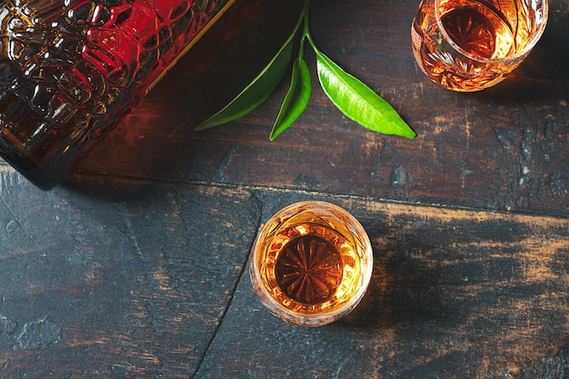 Tragos con licor de mandarina belga tradicional en una vieja mesa de madera oscura vista superior