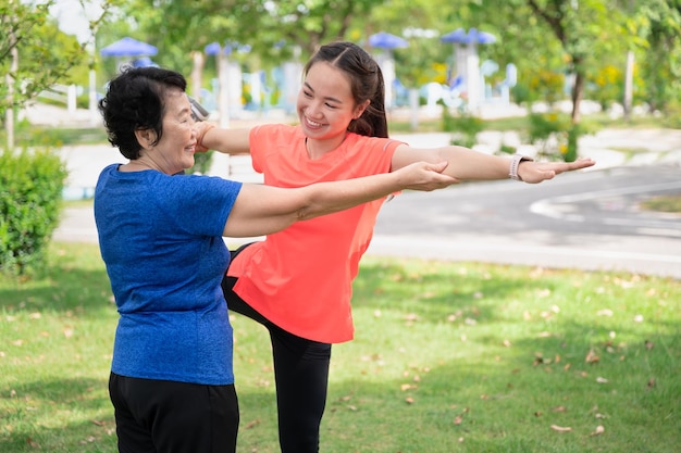 Trainer Asien Seniorin lehrt Teenager Frau Yoga im Garten zu trainieren